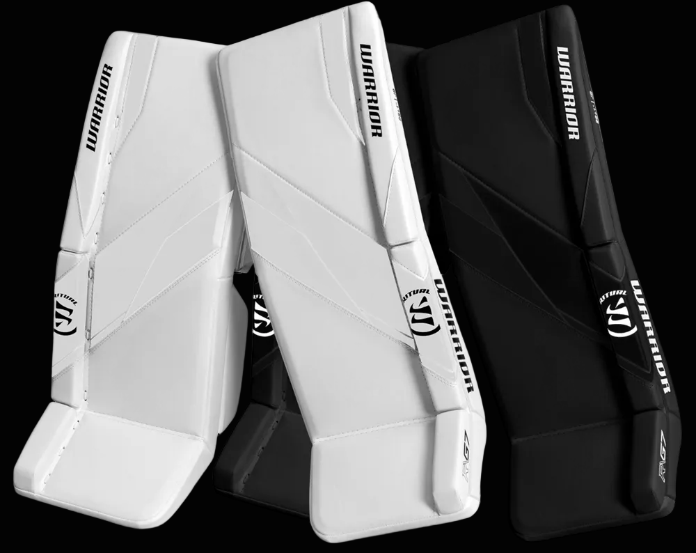 A pair of Warrior Ritual G7 Junior Leg Pads, one in white and one in black, with straps and padding visible.