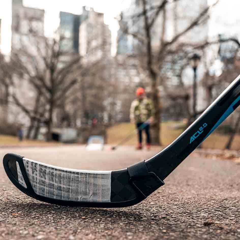 Bauer Blade Protector on hockey stick in outdoor park setting.