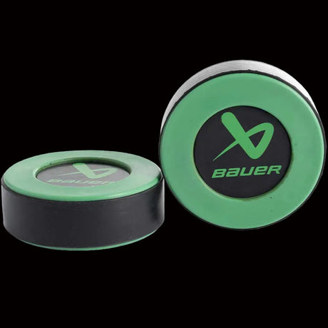 Two green hockey pucks with Bauer logo on a black background
