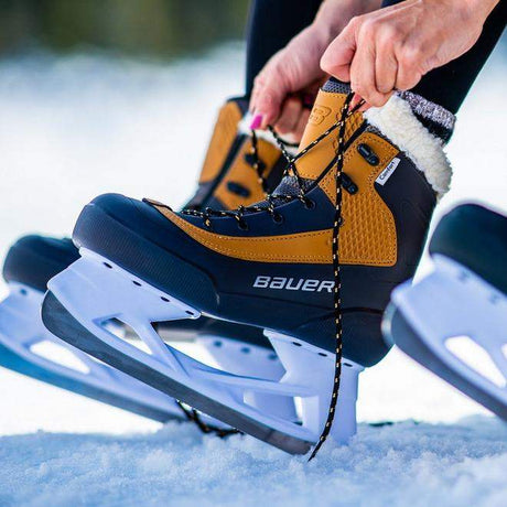 Bauer Whistler Lifestyle Ice Skate being laced up on a snowy surface, showcasing comfort and style.